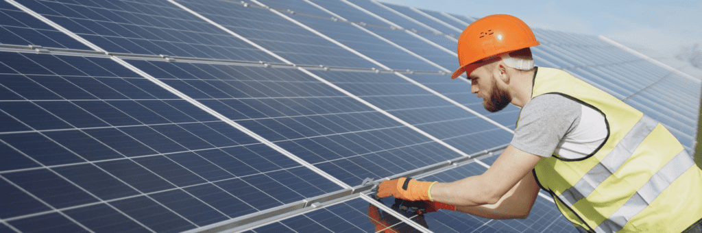 Een arbeider werkt aan een zonnepaneel.