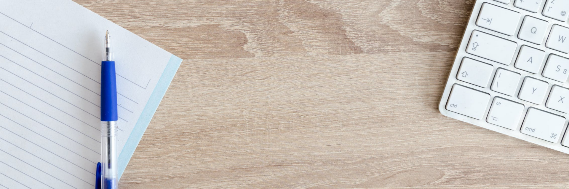 Een notitieboekje en een pen op een houten bureau.