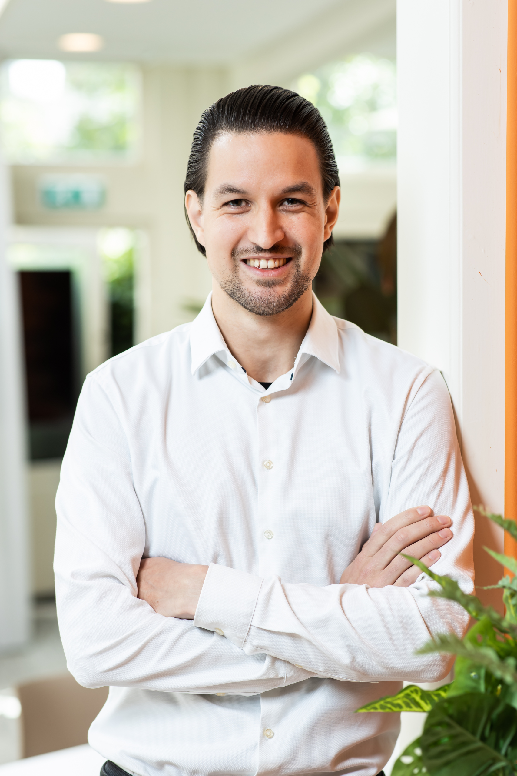 Een man staat met zijn armen over elkaar in een kantoor.