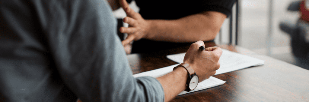 Twee mensen zitten aan een tafel en praten met elkaar.