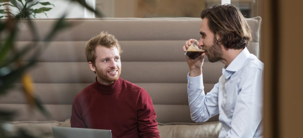 Twee mannen zitten op een bank in een kantoor.