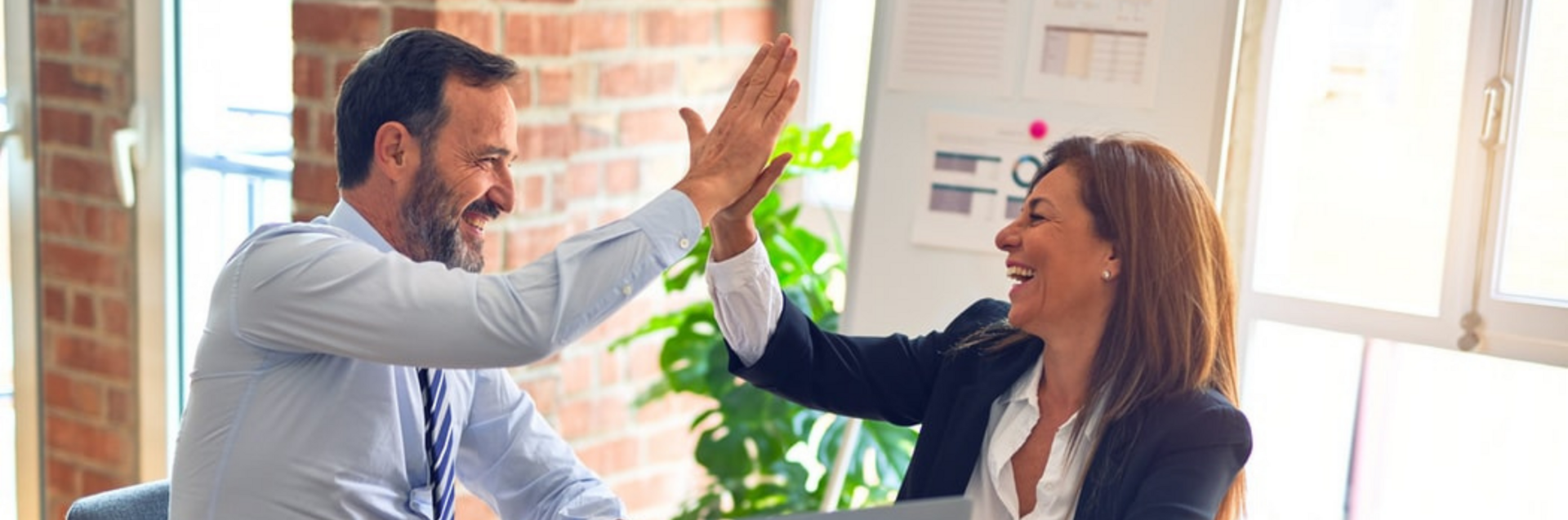 Twee zakenmensen geven elkaar high fives in een kantoor.