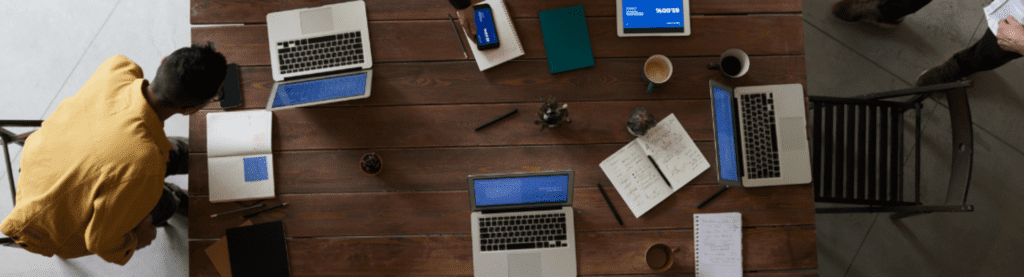 Een groep mensen die aan een tafel op laptops werken.