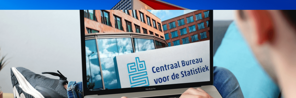 Een man zit op een bank met een laptop voor hem.