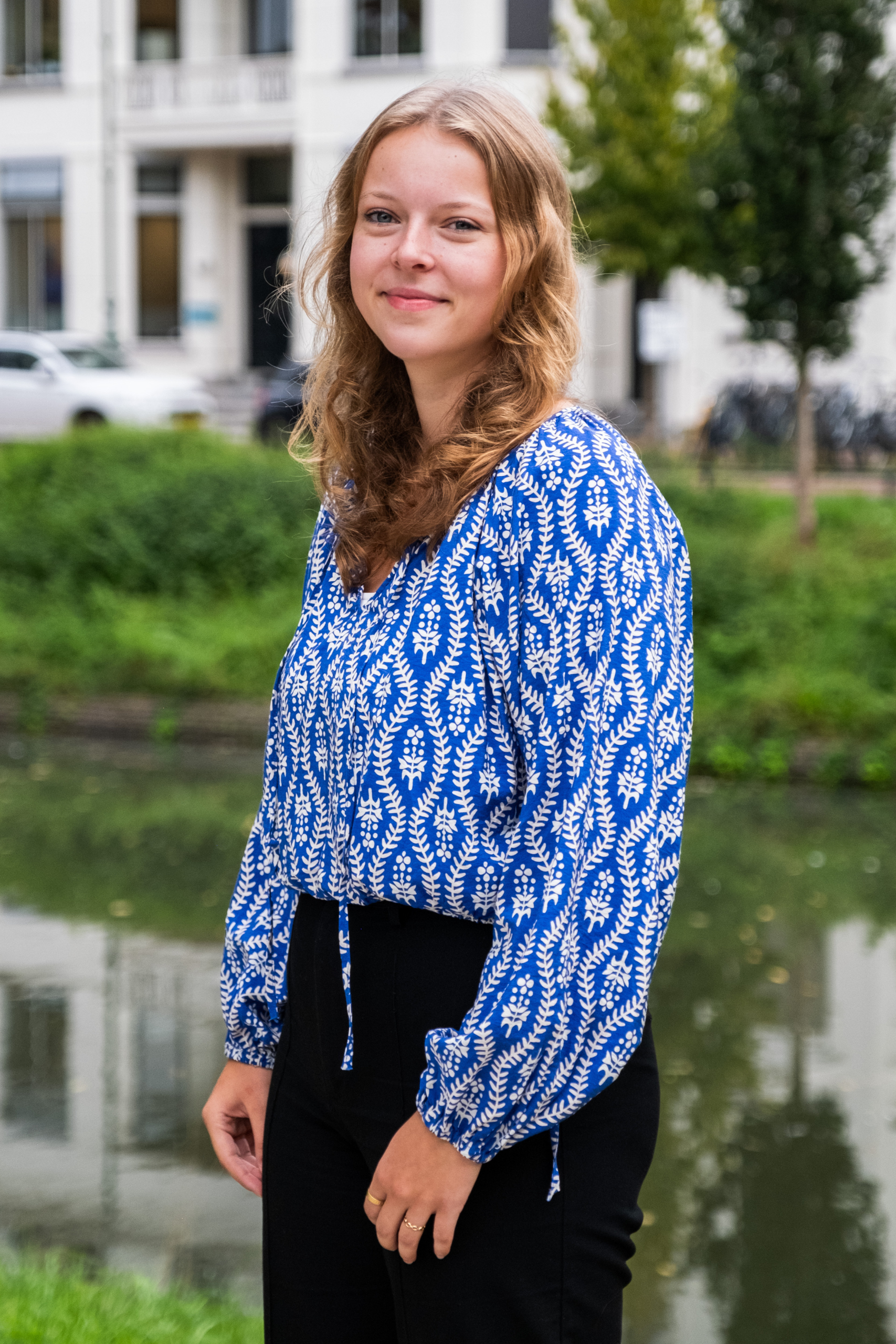 Een jonge vrouw die voor een watermassa staat.