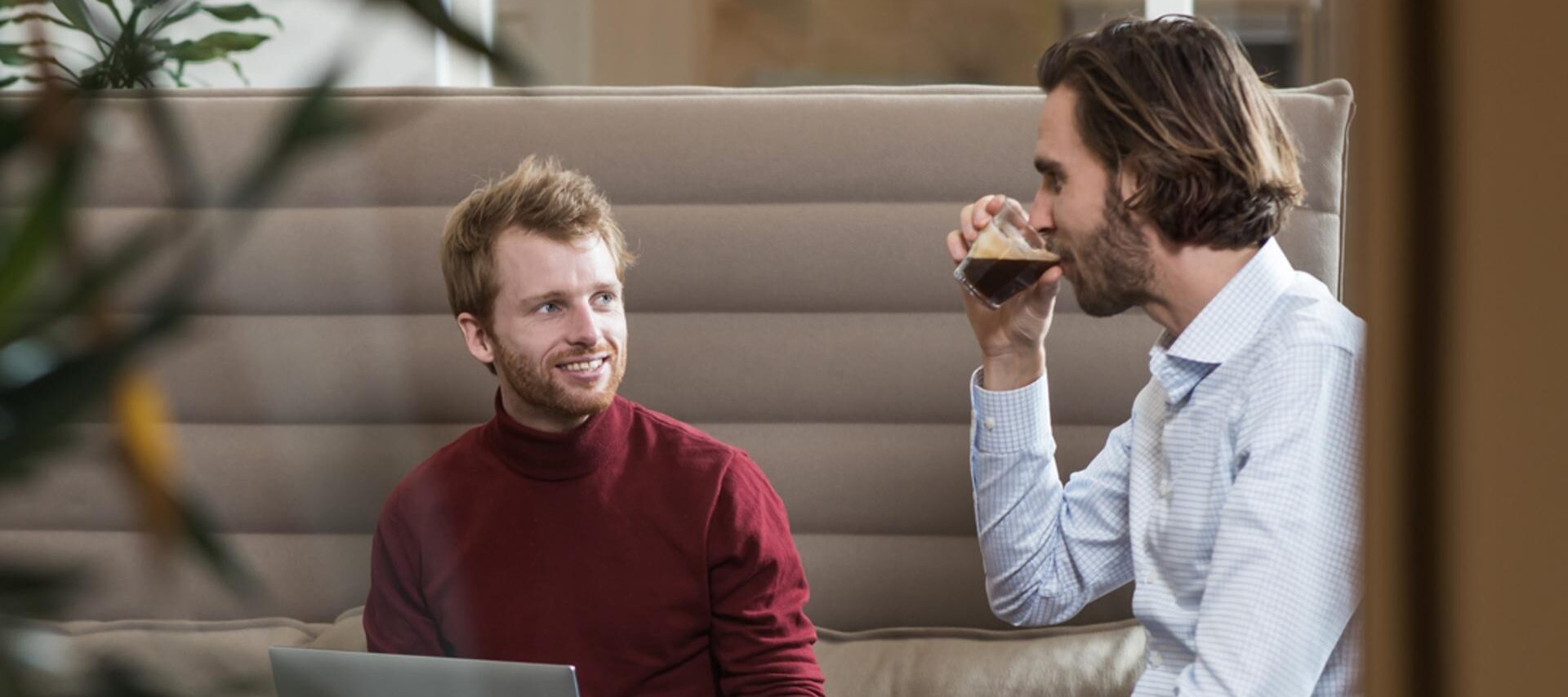 Twee mannen zitten op een bank in een kantoor.