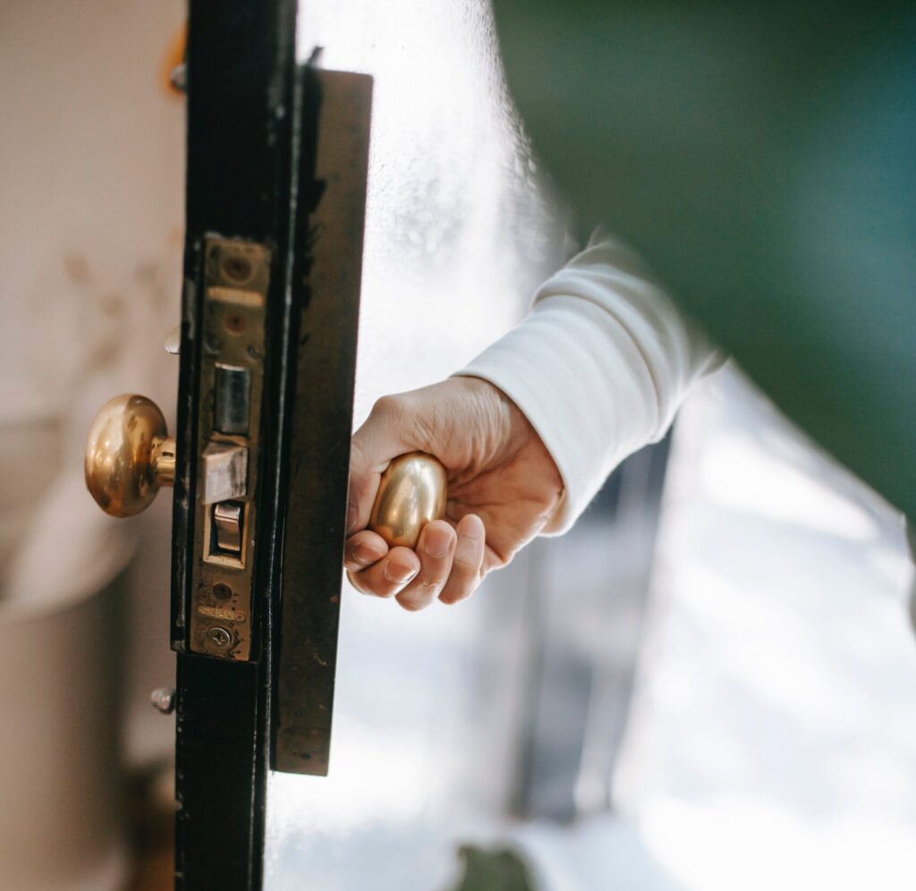 Een persoon die een deur opent met een sleutel.